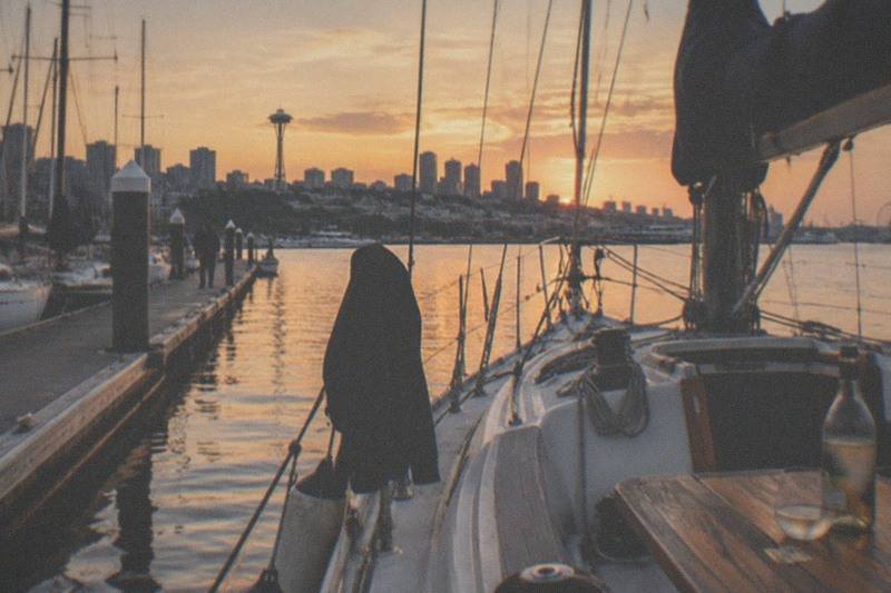 Tall ship under a full rig at sunset, passengers along the rails; the Evening Colors Sunset Sail Tour by Seattle's Tall Ship runs two hours, books from $65 per person and carries a 4.8 rating across 723 reviews.