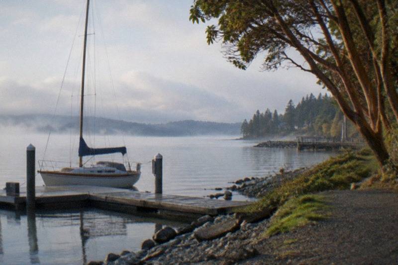 Sailboat clearing Bainbridge Island toward open water; the Guided Seattle Sailing Adventure by Sail Rumbera runs two hours, books per group from $360 and holds a 5 rating across 85 reviews.
