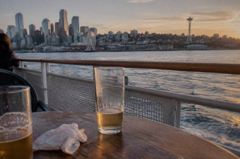 Harbor boat in evening light, passengers with drinks in hand; the Seattle Happy Hour Cruise by Argosy Cruises lasts 1 hour 30 minutes, starts at $57.32 per person and rates 4.2 across 45 reviews.