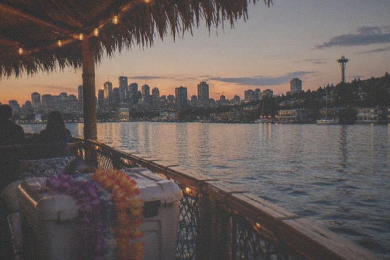 A tiki boat out on Lake Union with the Seattle skyline in the background, chartered privately through Seattle Tiki Boat for up to fifteen guests over one and a half to two hours, rated 5 across 3 reviews.