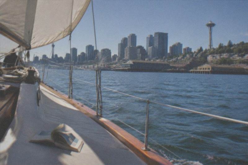 Bow of a 70ft sailboat cutting calm water under sail; Seattle's Original Sailing Cruise, established 1984, is a BYOB outing of about two hours with Sailing Seattle, from $60 per person, rated 4.9 across 215 reviews.
