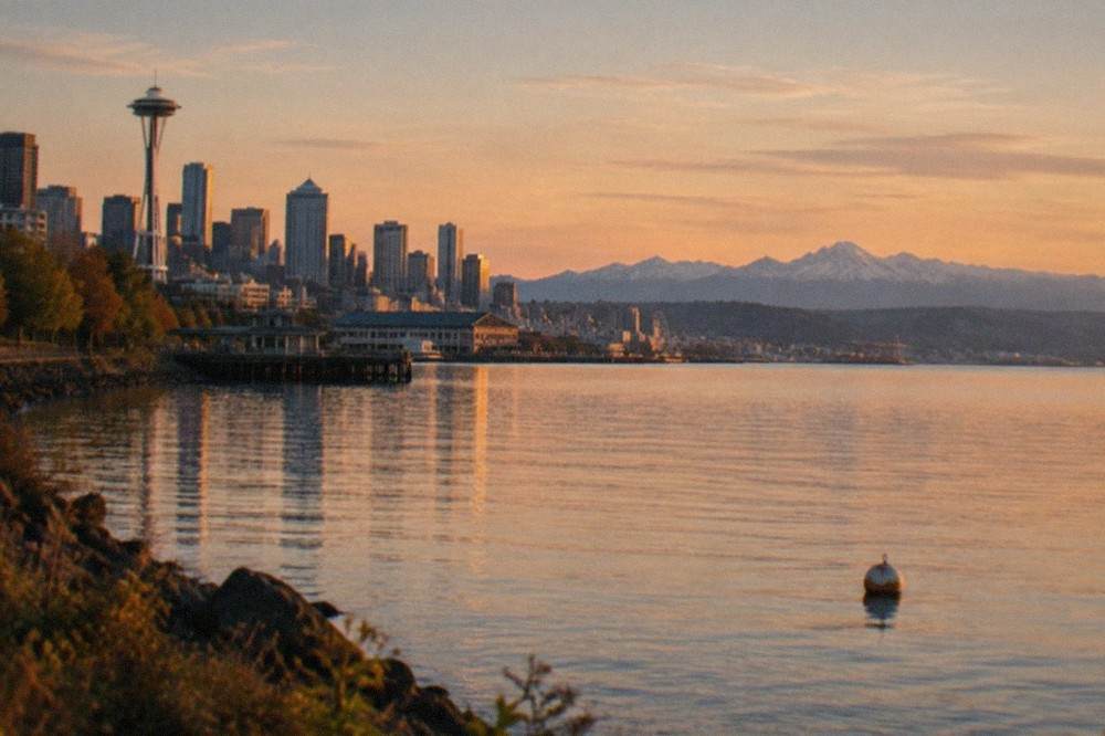 Golden evening light over Puget Sound with the Olympic Mountains on the horizon and a calm water surface.