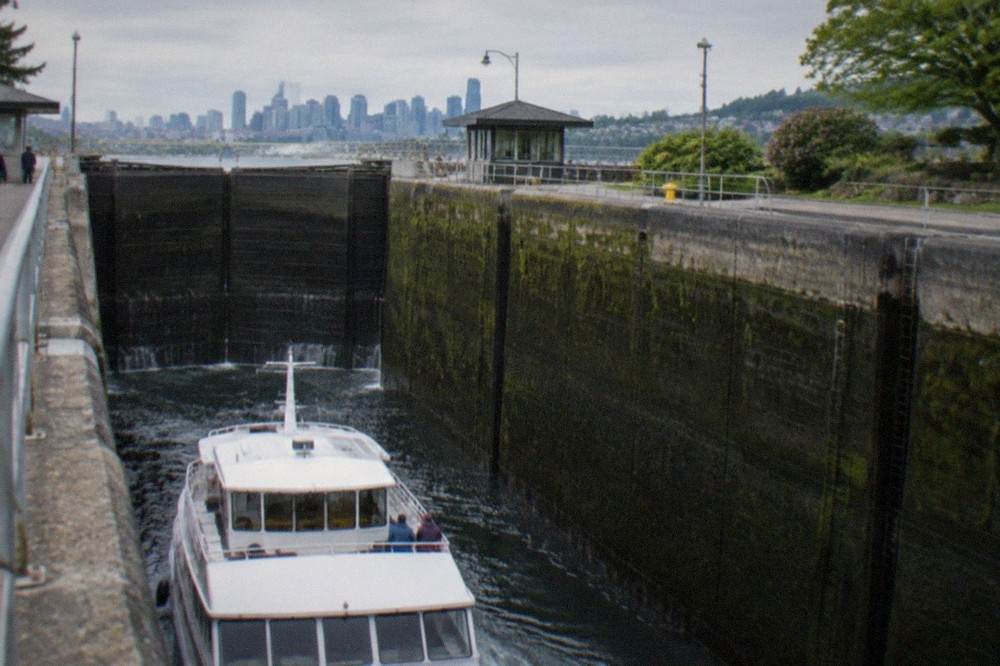 A tour boat descending in the large lock chamber as water drains toward Puget Sound level