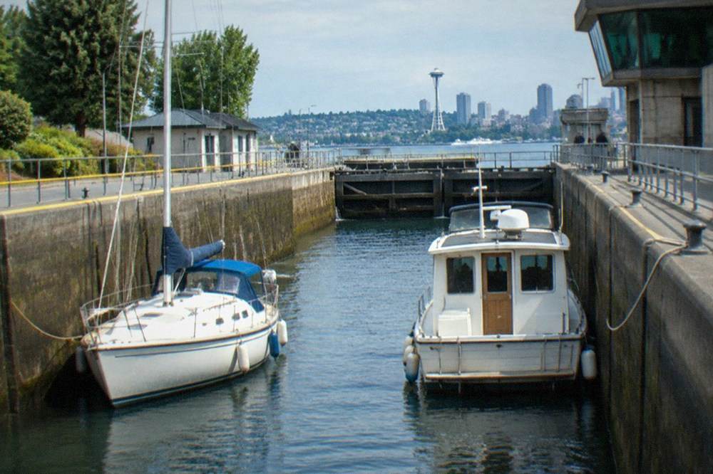 A small sailboat and a powerboat sharing the small lock chamber at the Ballard Locks