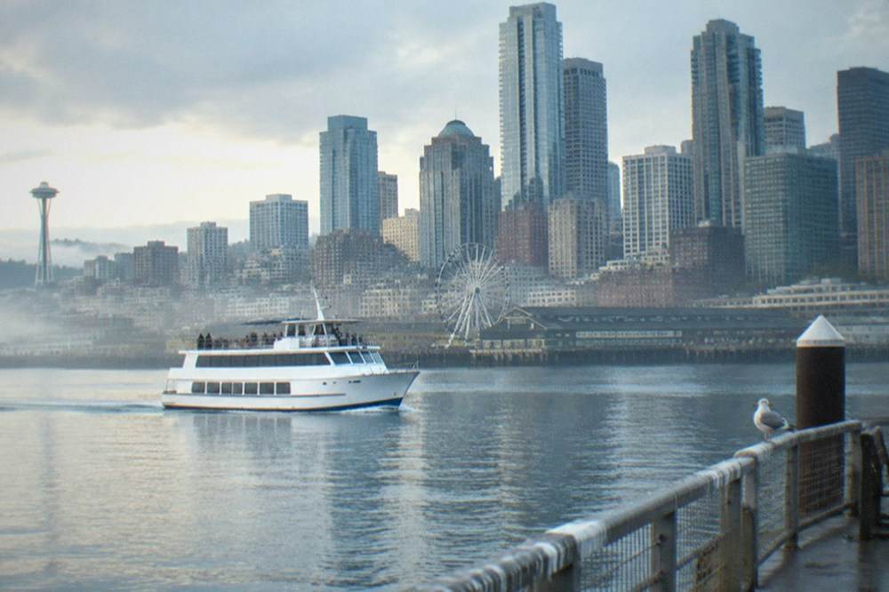 A small cruise boat underway on Elliott Bay with downtown Seattle office towers in the background