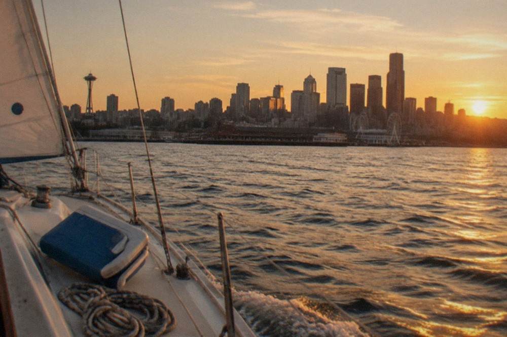 A sailing boat passing the Seattle skyline on Elliott Bay at golden hour