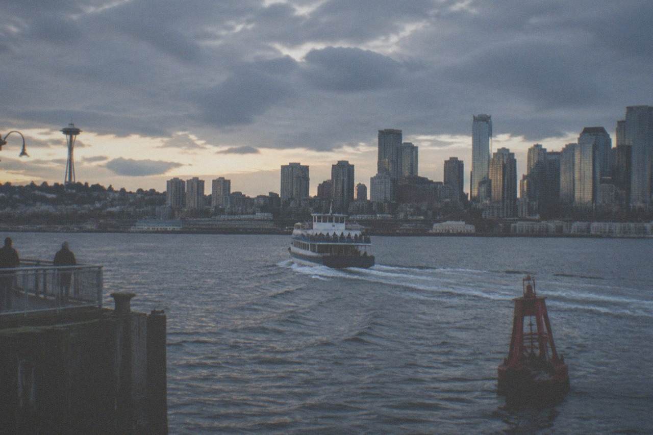 A sightseeing boat cruising on Elliott Bay with the Seattle skyline behind it