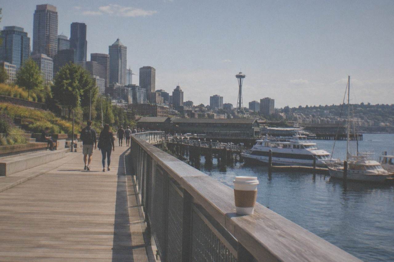 View along the Seattle waterfront promenade with Elliott Bay, piers and moored boats in afternoon light