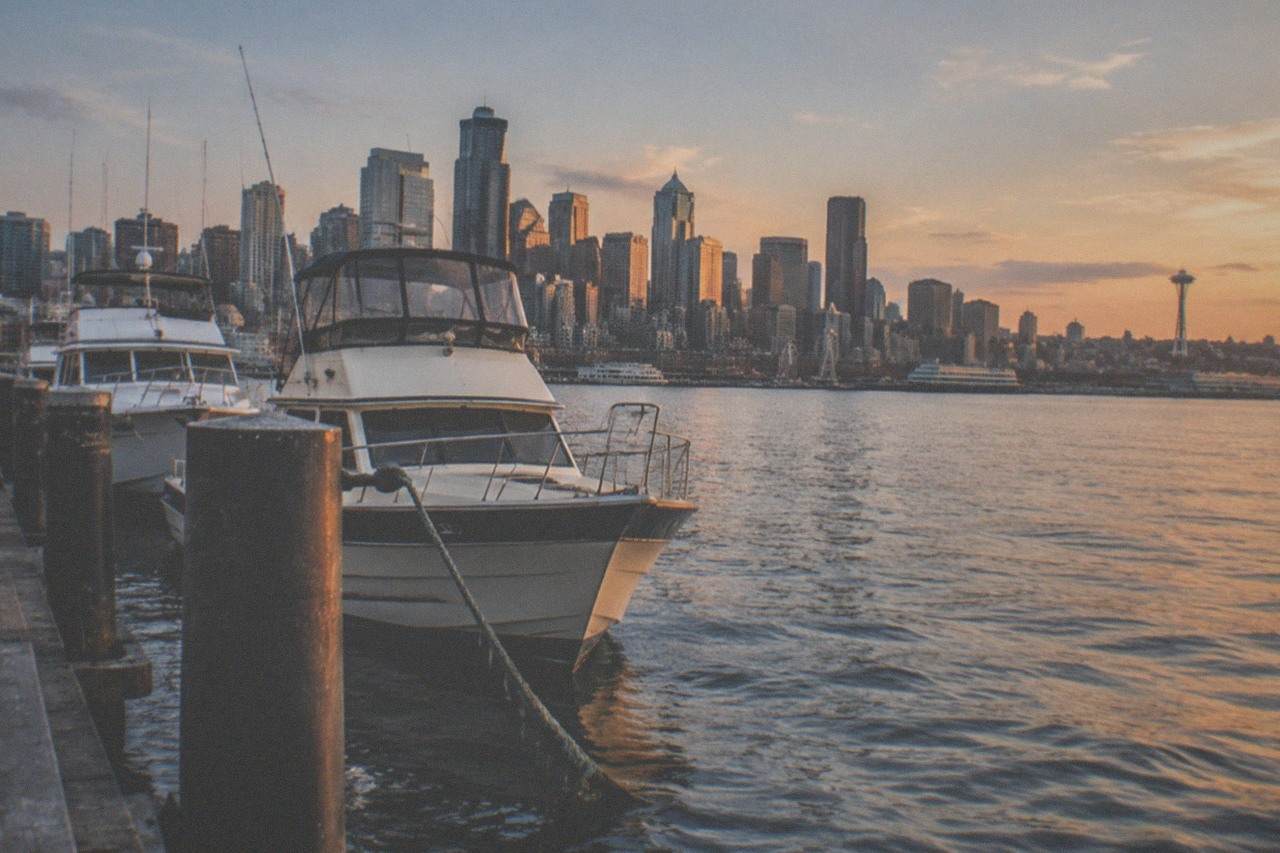 Seattle skyline and moored boats across Elliott Bay at dusk