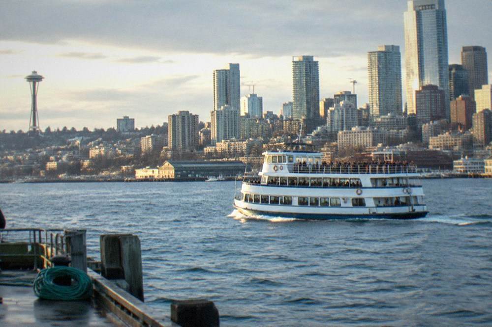 A narrated sightseeing boat cruising on Elliott Bay with the Seattle skyline behind it