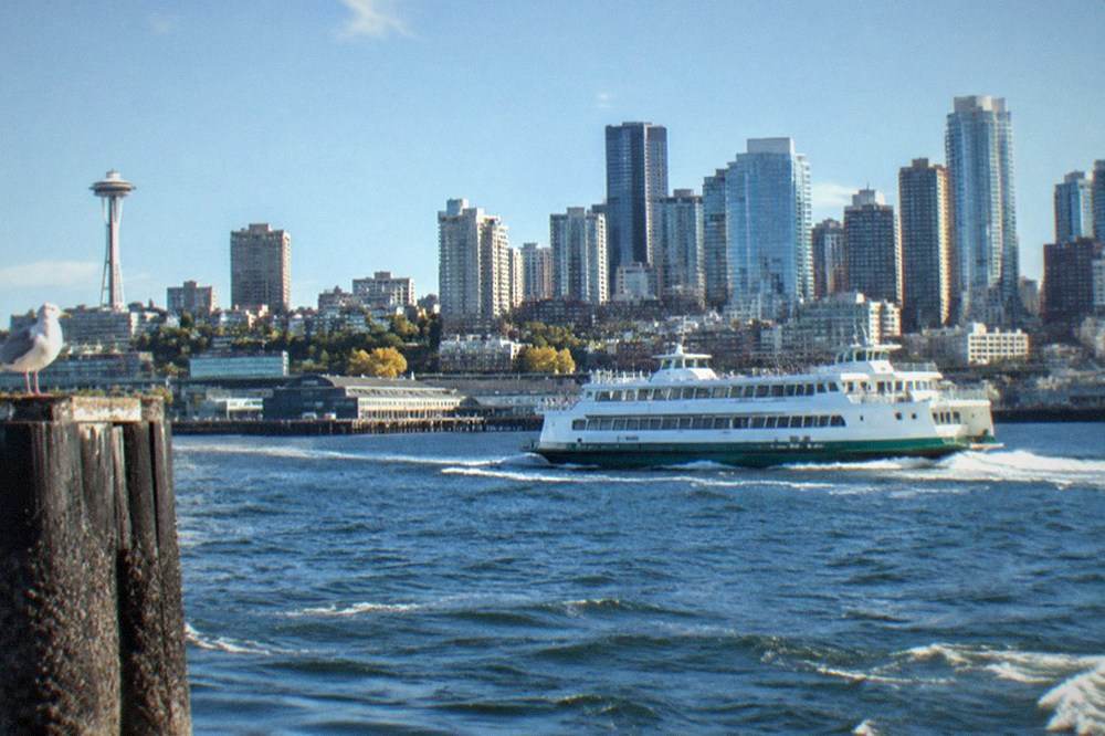 Tour boat cruising on Elliott Bay with downtown Seattle skyline behind it
