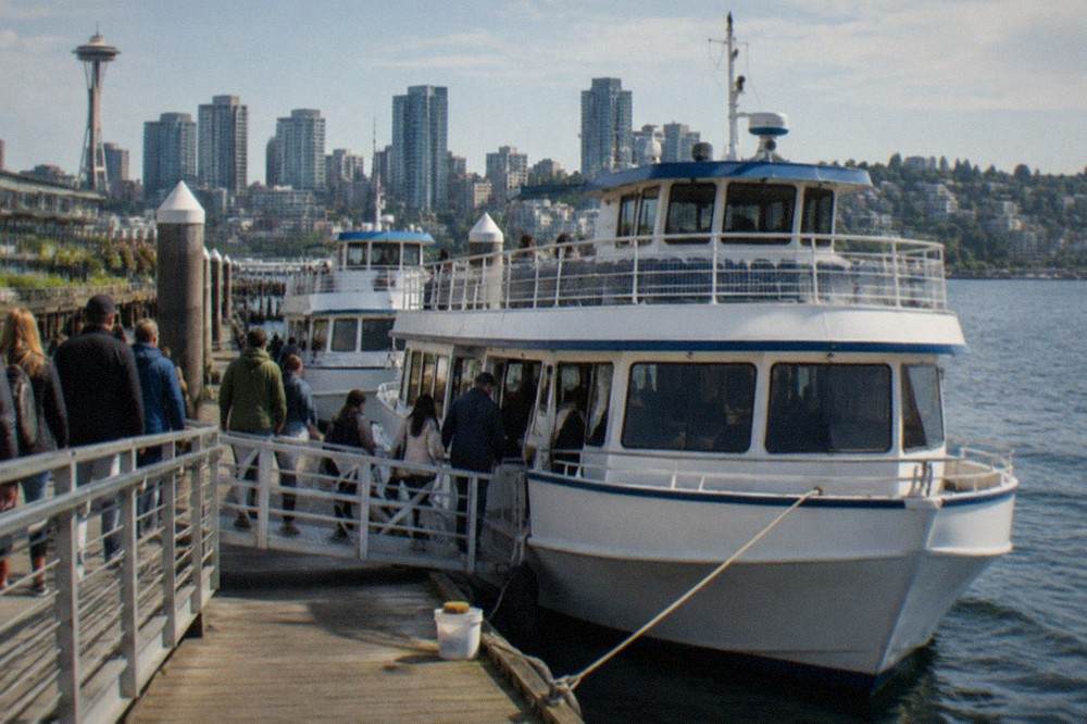 Tour boats moored along the Seattle waterfront with passengers boarding at a pier