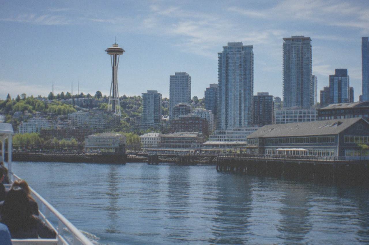 A sightseeing boat cruising on Elliott Bay with the Seattle skyline and Space Needle behind it