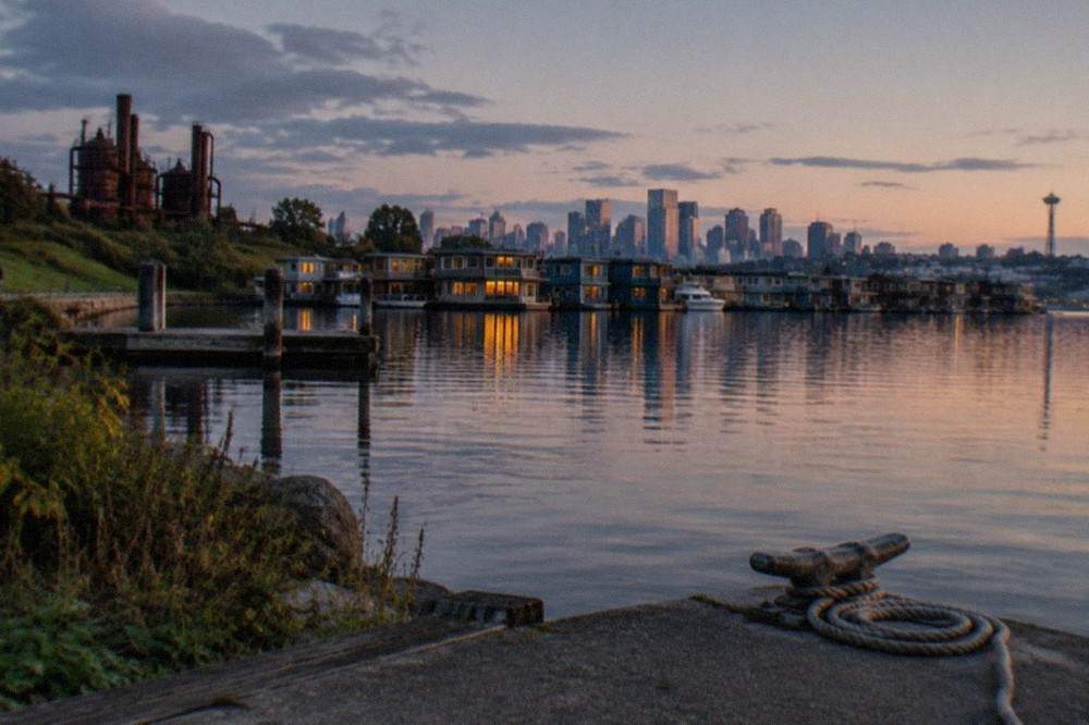 A calm Lake Union at dusk with houseboats and a distant downtown skyline in soft light