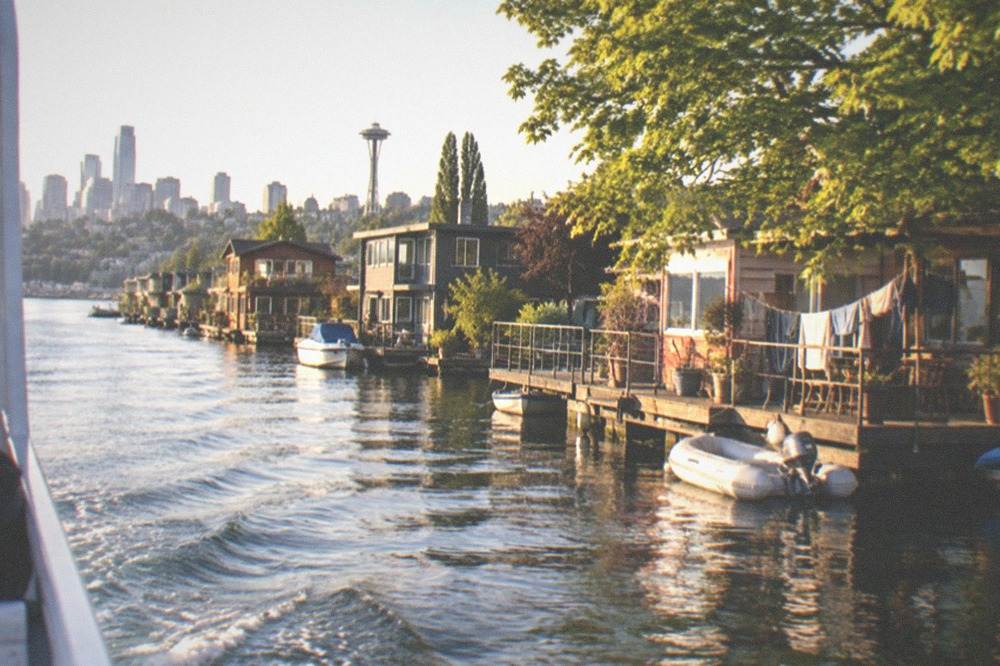 A tour boat motoring along the ship canal past houseboats and shore-side homes