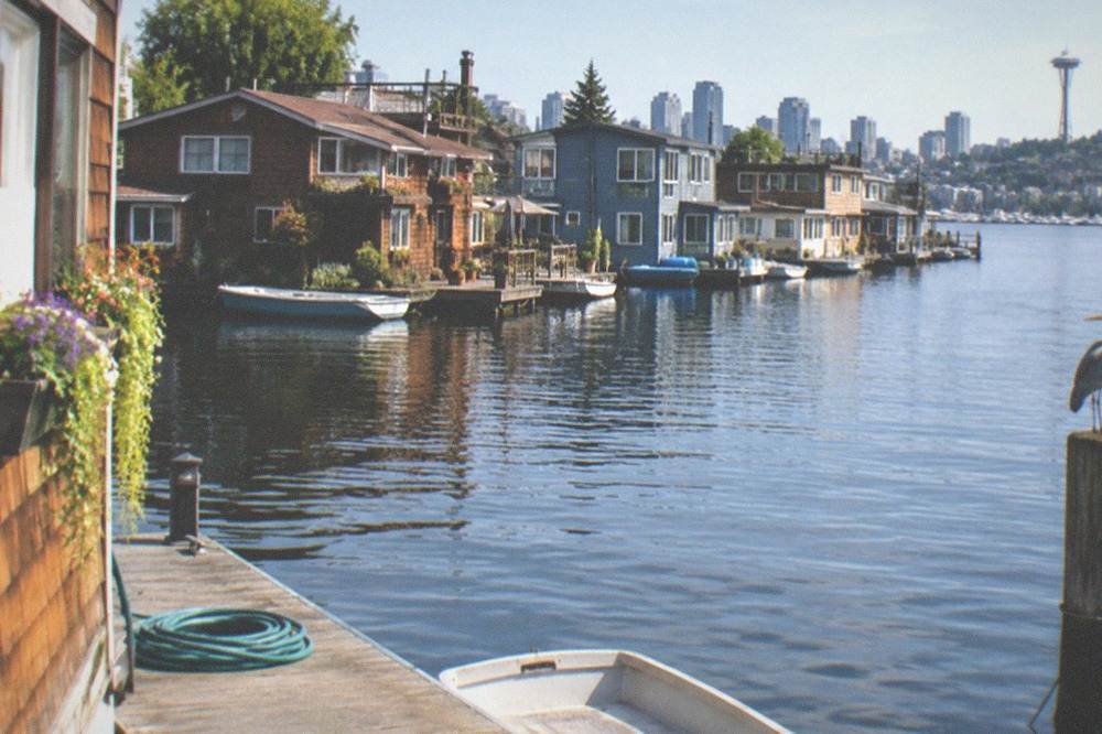 Floating homes and moored boats along a Lake Union dock at midday