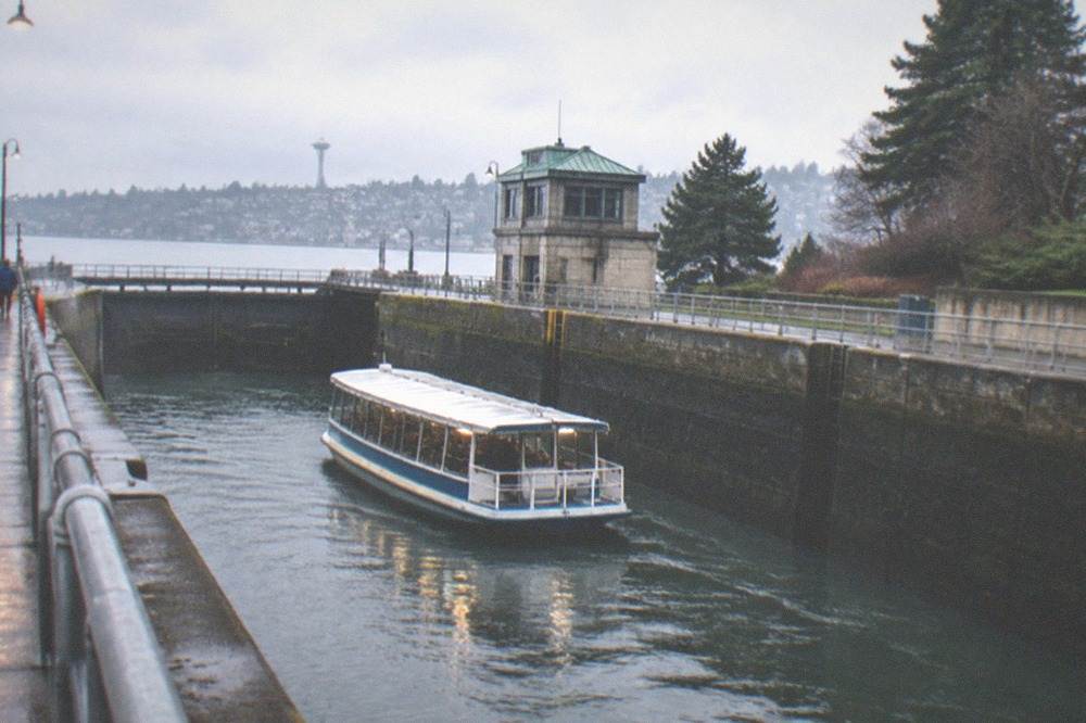 A covered tour boat moving through the Ballard Locks in overcast winter weather
