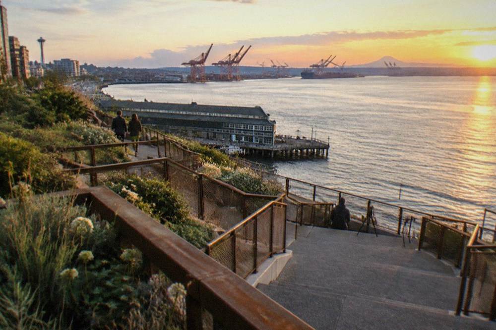 Elevated walkway with terraces and railings overlooking Elliott Bay and moored boats