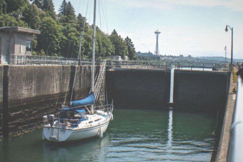 Concrete lock gates holding back water with a sailboat inside the lock chamber