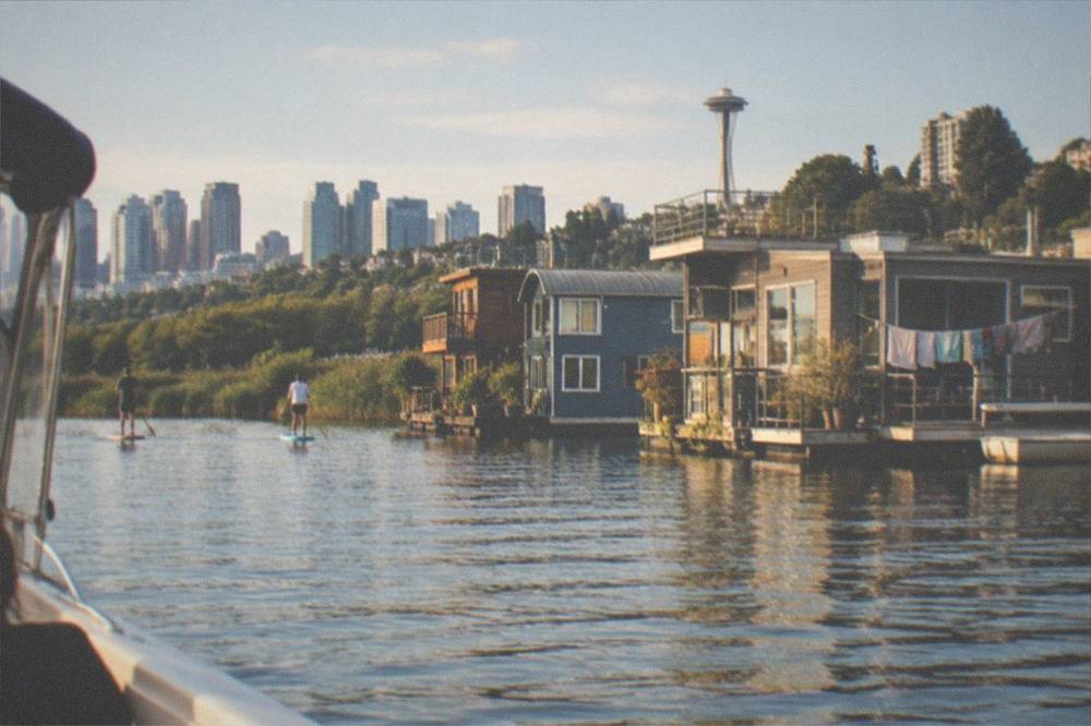 A small private charter boat cruising past floating homes on Lake Union