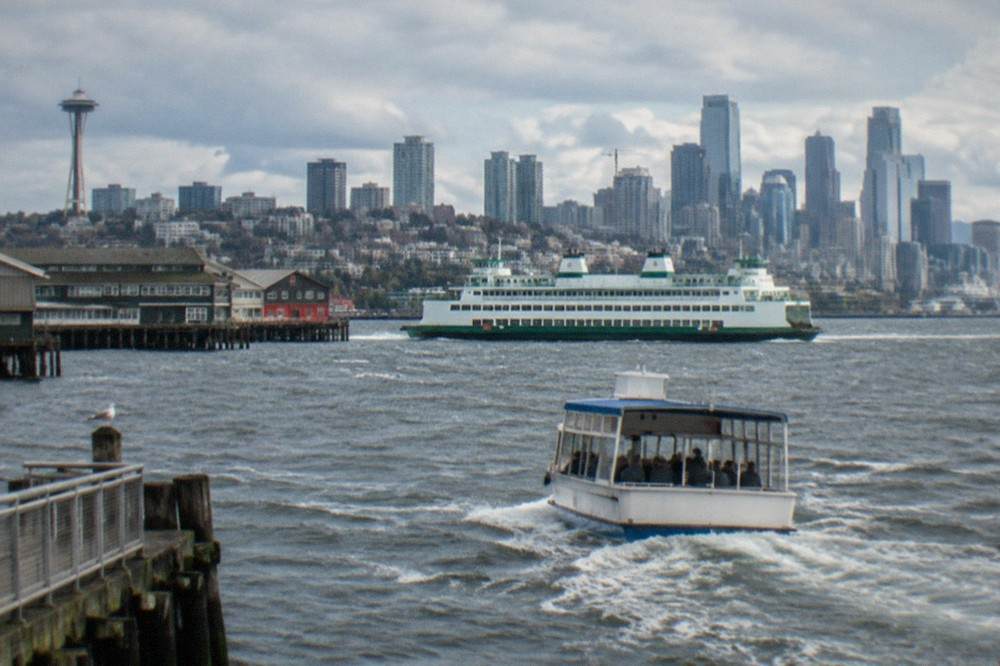 A state ferry and a small tour boat sharing Elliott Bay near the Seattle waterfront