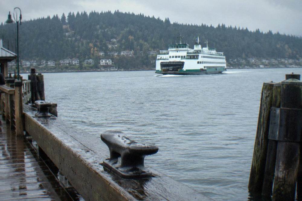 A Washington state ferry crossing Puget Sound toward Bainbridge Island with forested hills beyond