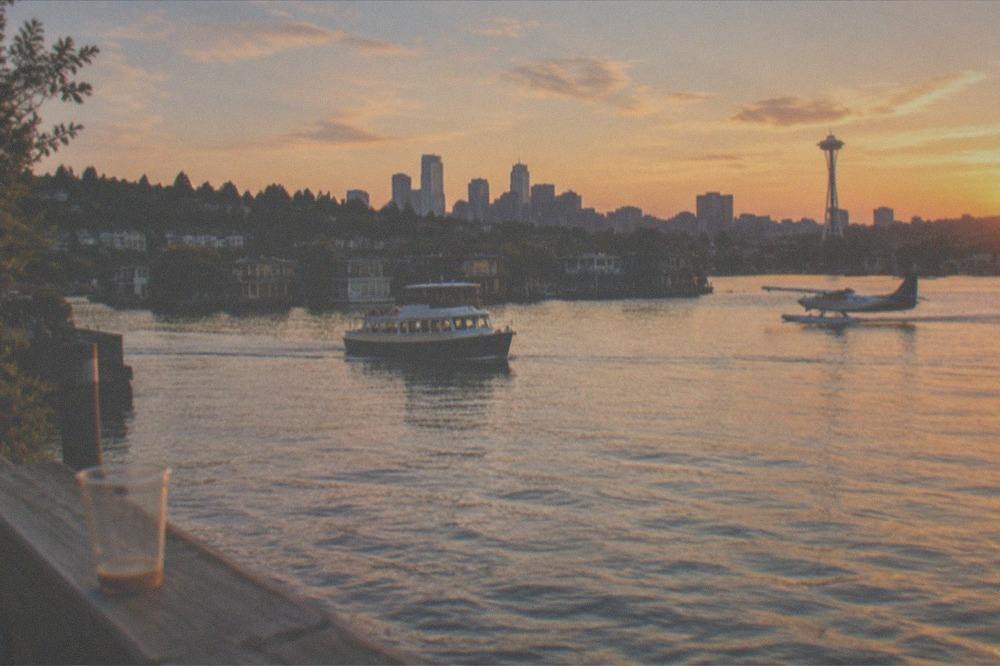 A cruise boat and a floatplane visible together over Lake Union at golden hour