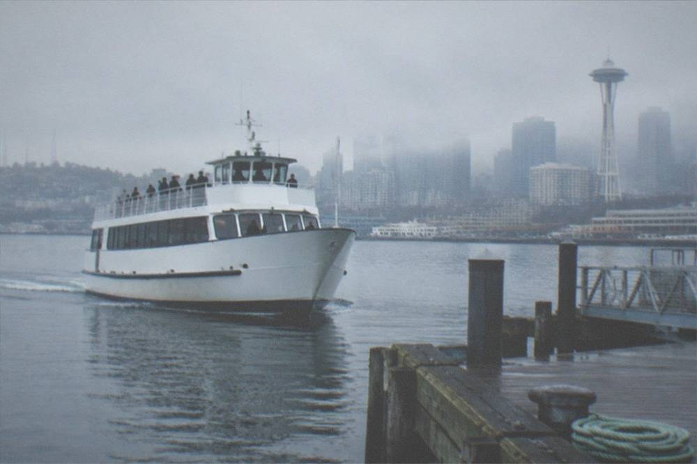 Tour boat departing a downtown Seattle pier with passengers on deck