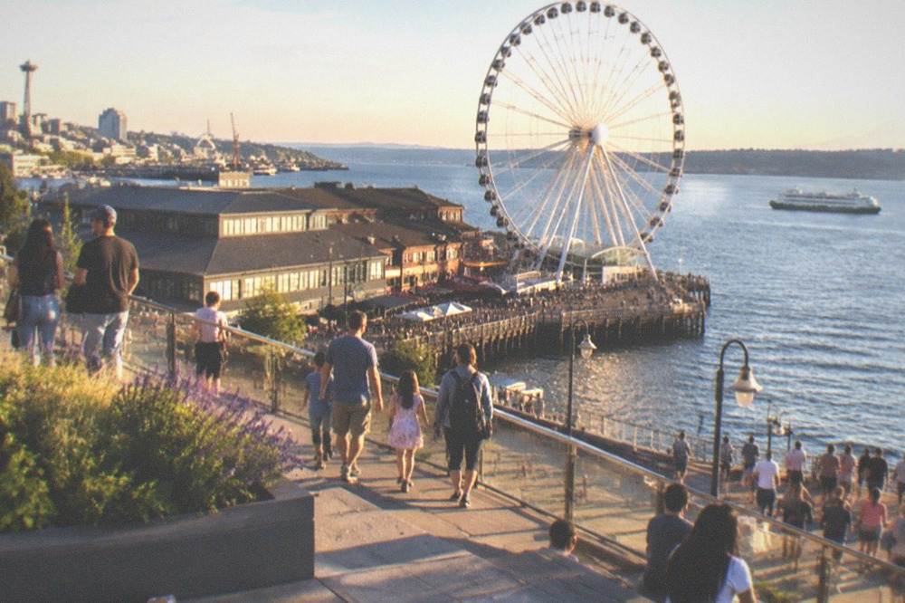 Crowded waterfront promenade in summer with the Seattle Great Wheel in the background