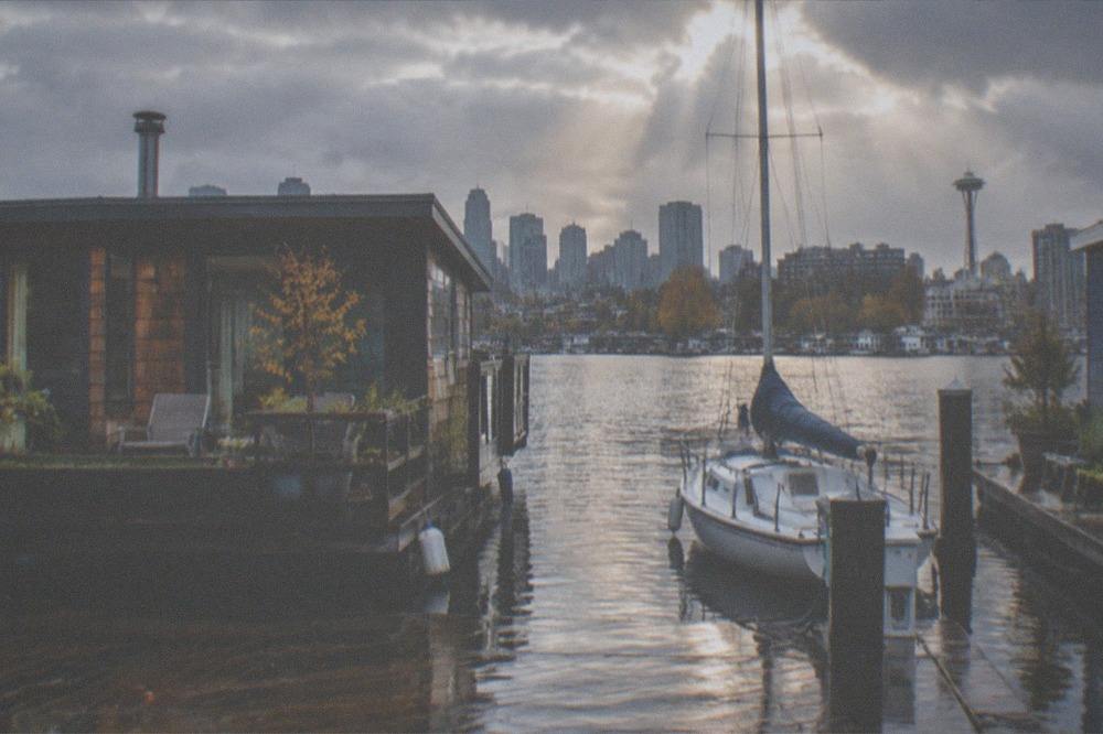 Rain clouds parting over Lake Union with houseboats and wet dock planks in the foreground